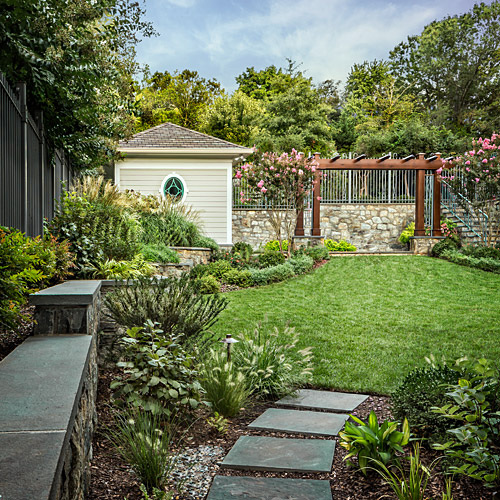 A garden shed and arbour at the end of a planted path